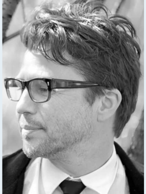 Black and white closeup image of a man with glasses looking to the side